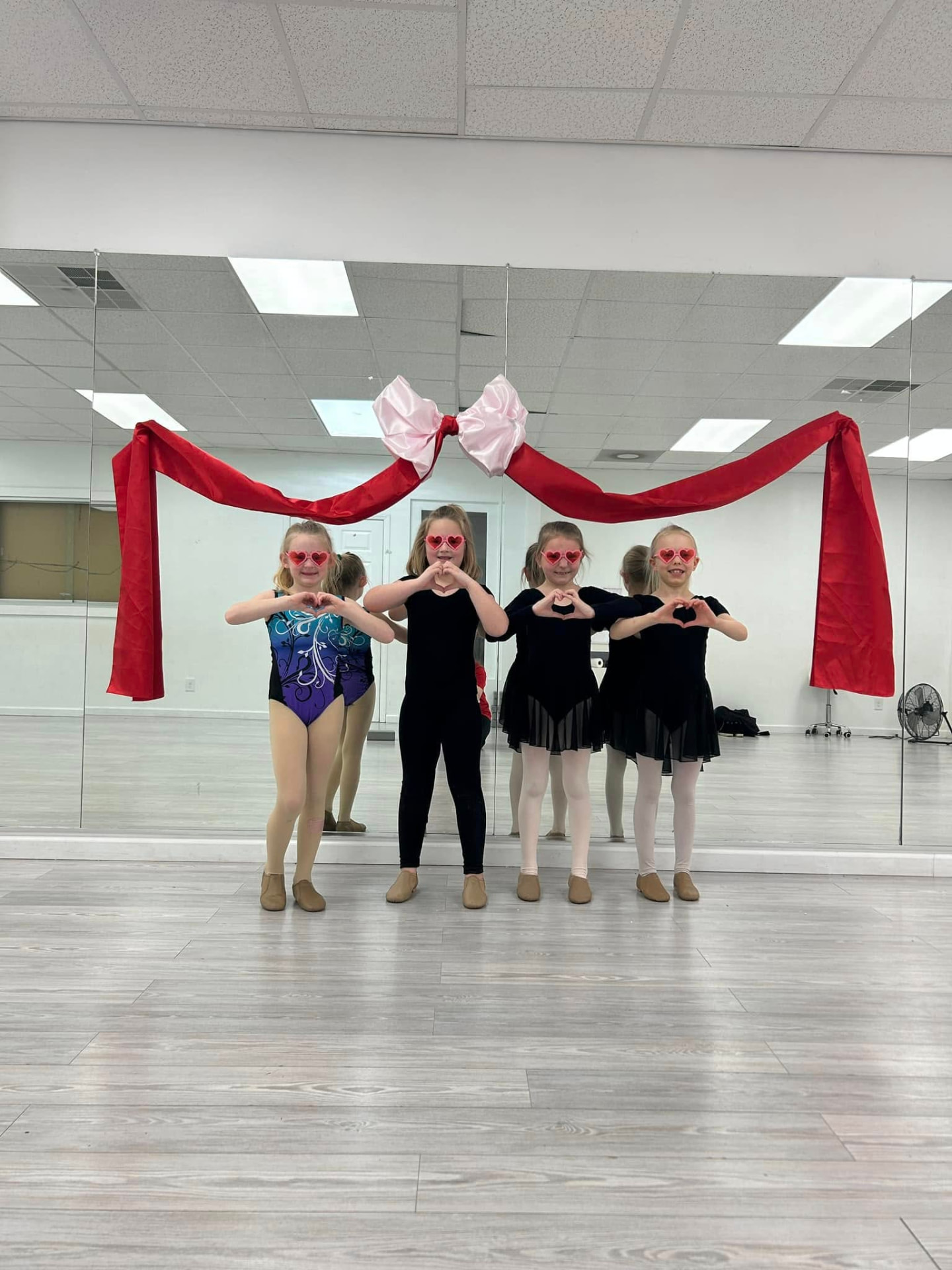 A long line of ballet students in black leotards at the barre