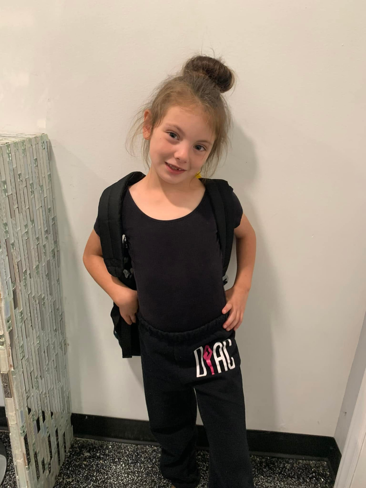 A dancer with her backpack and Dance Perfections joggers ready for class